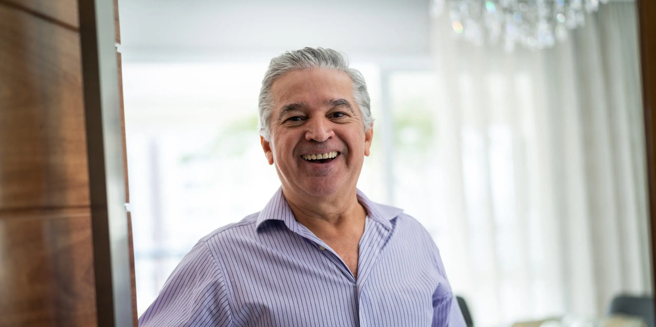 Older smiling man opens the front door