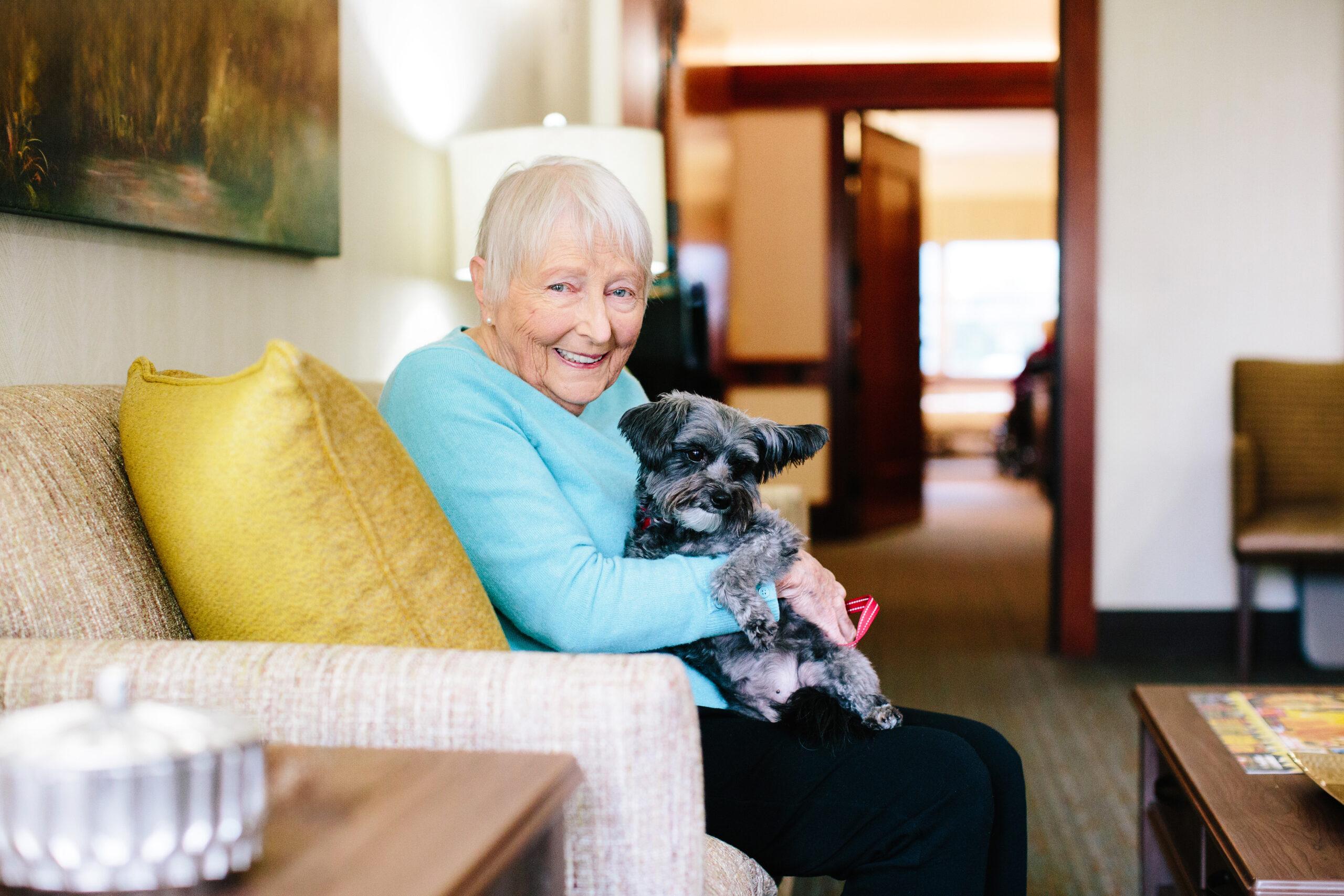 A smiling senior woman holds a dog